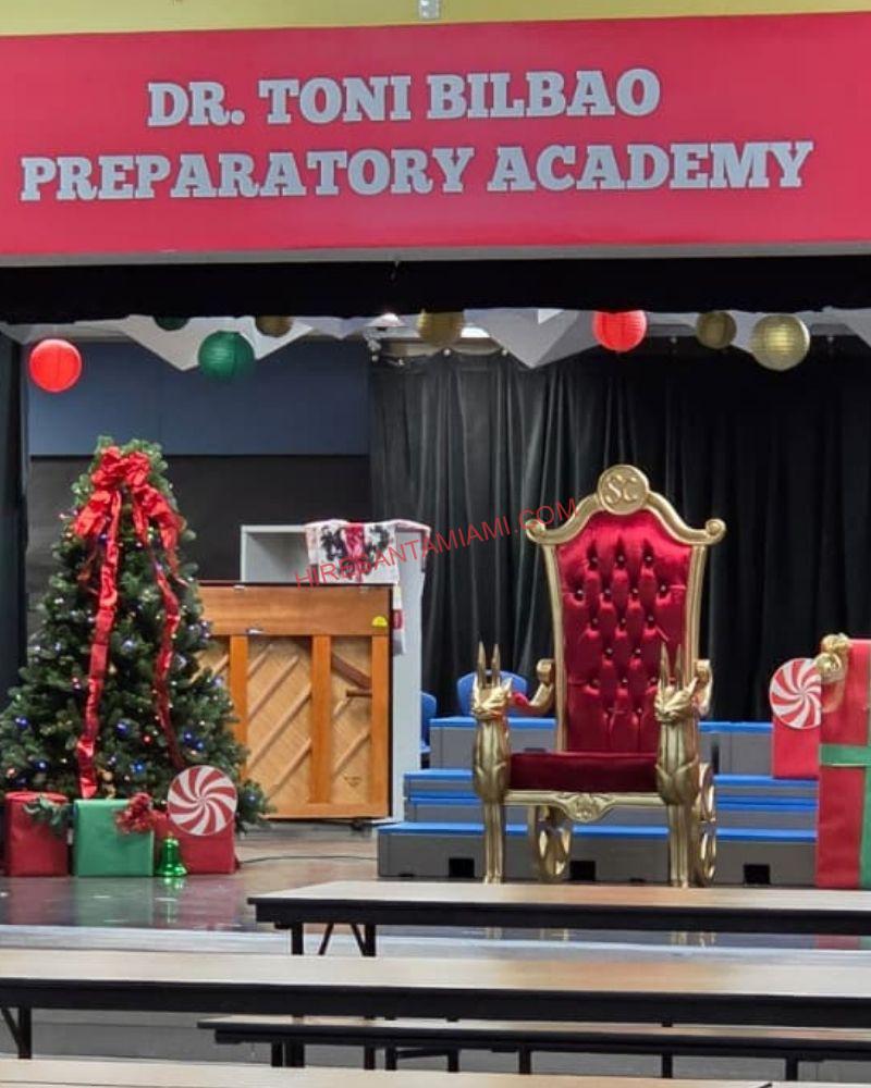 Two Santa thrones on a decorated school stage in Doral for a holiday program